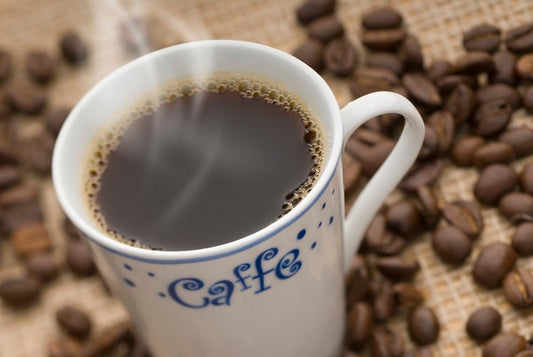 a cup of coffee sitting on top of a pile of coffee beans
