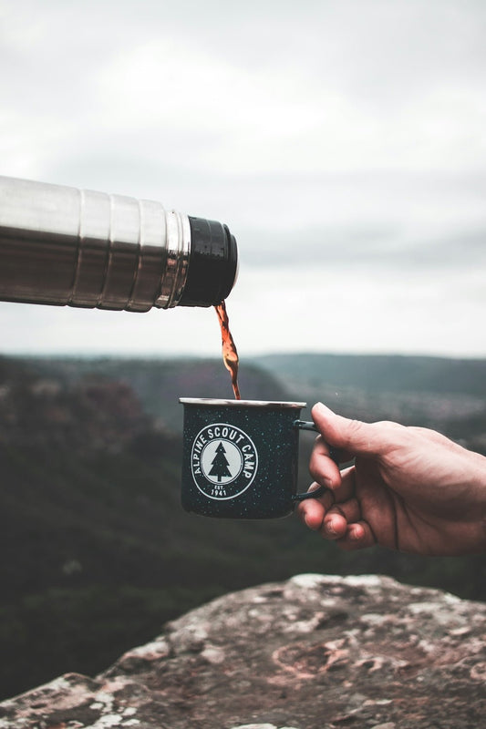 a person holding a coffee cup with a mountain in the background