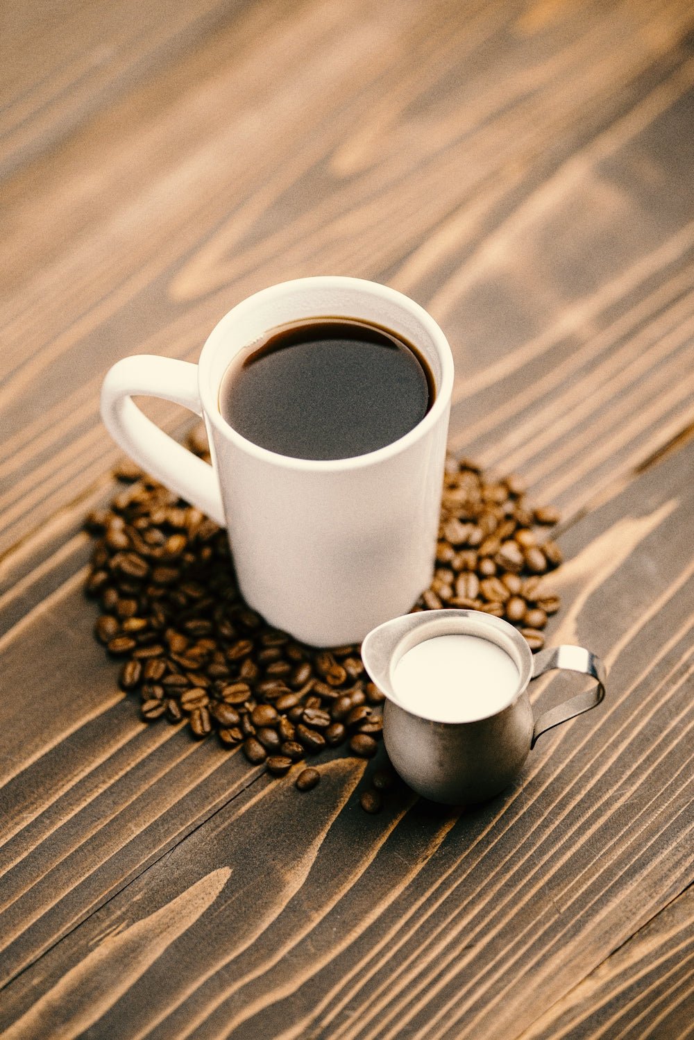 white ceramic mug with coffee on brown wooden table