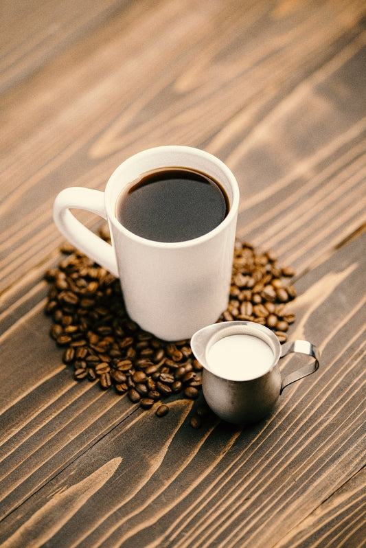white ceramic mug with coffee on brown wooden table