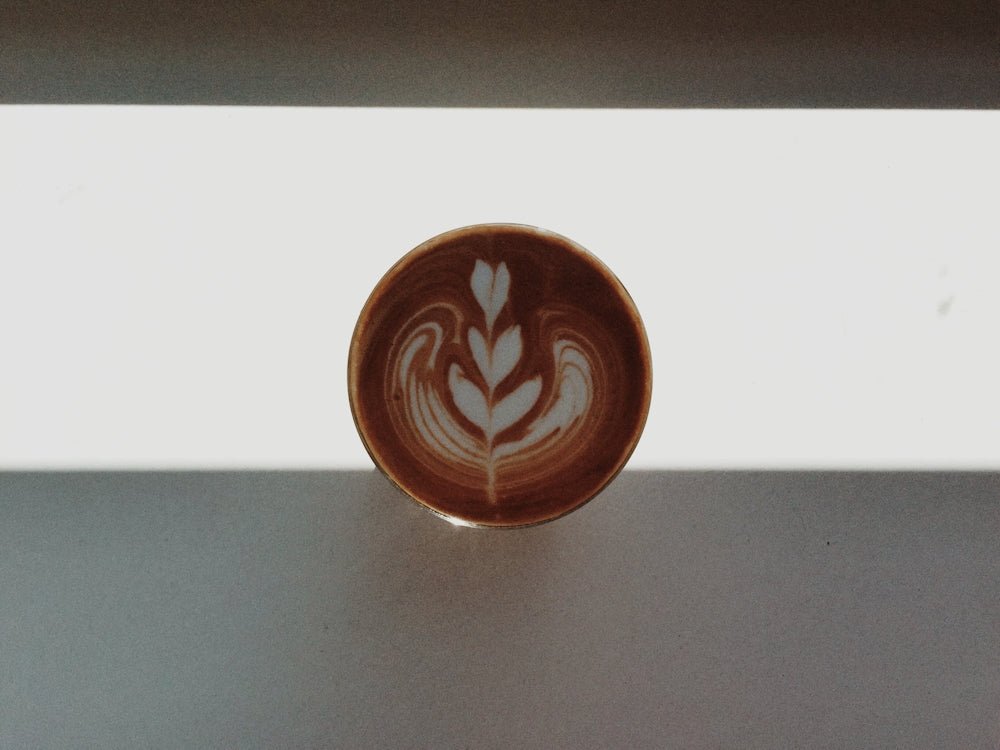 a cup of coffee with a leaf design on it