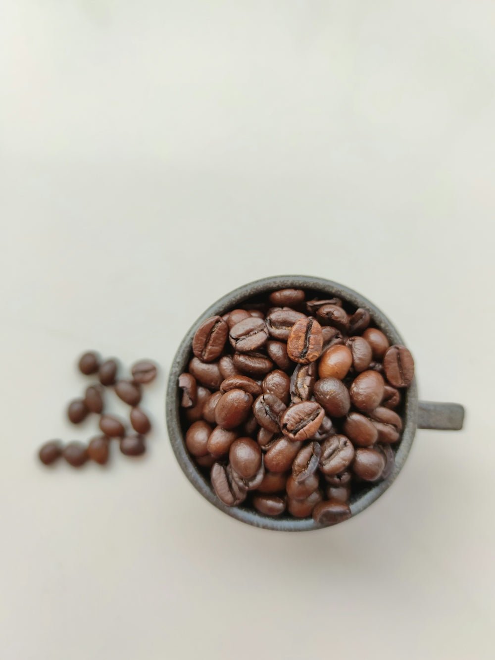 brown coffee beans on black ceramic mug