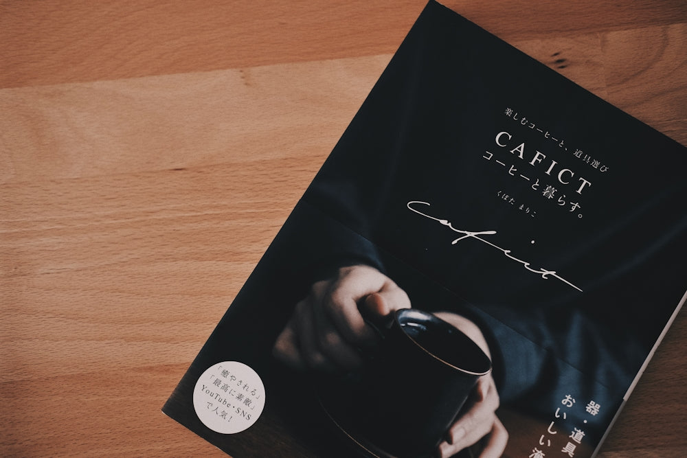 a person holding a coffee cup on top of a book
