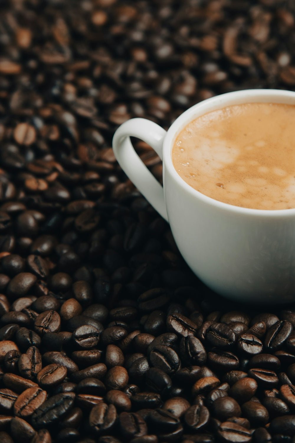 a cup of coffee sitting on top of a pile of coffee beans