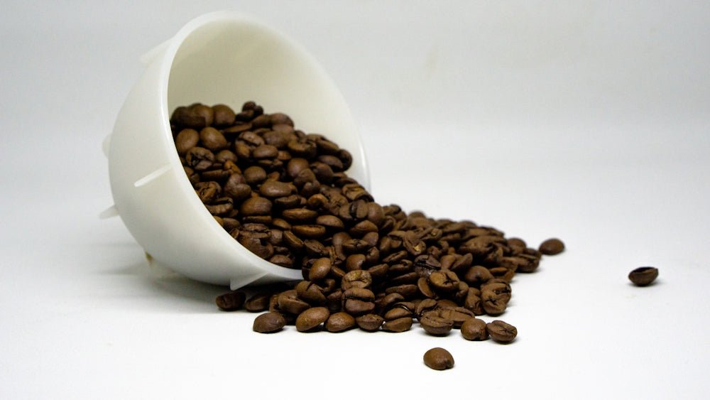 a cup filled with coffee beans spilling out of it