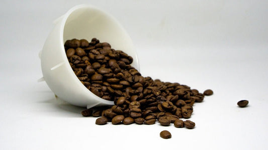 a cup filled with coffee beans spilling out of it