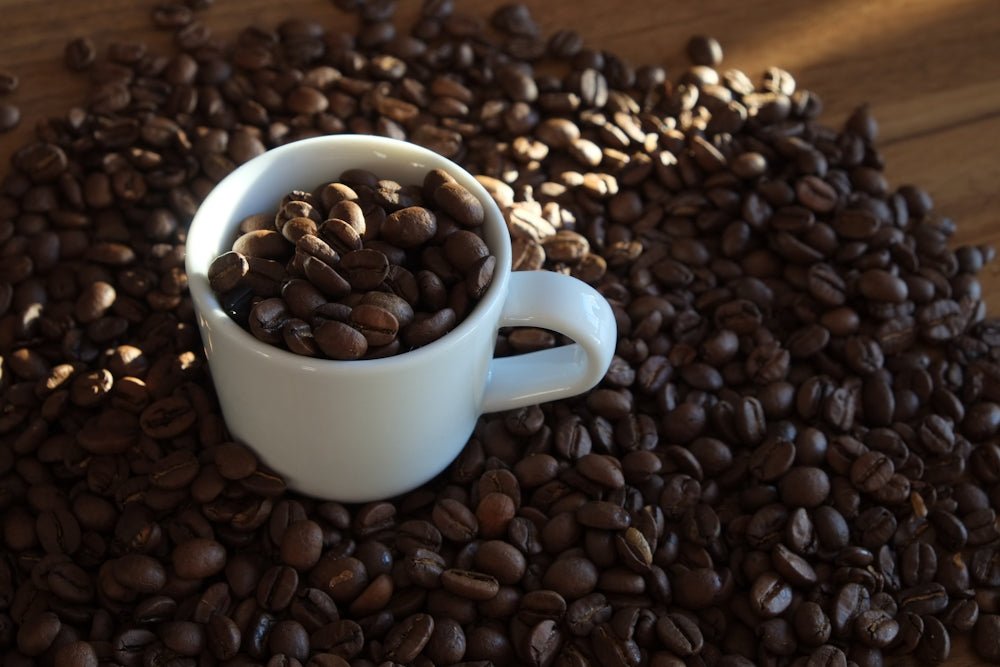 a white cup filled with coffee beans on top of a wooden table