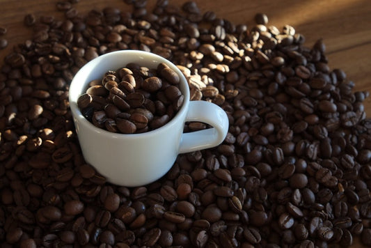 a white cup filled with coffee beans on top of a wooden table