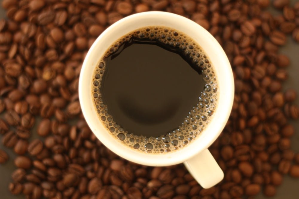 A cup of coffee sitting on top of a pile of coffee beans