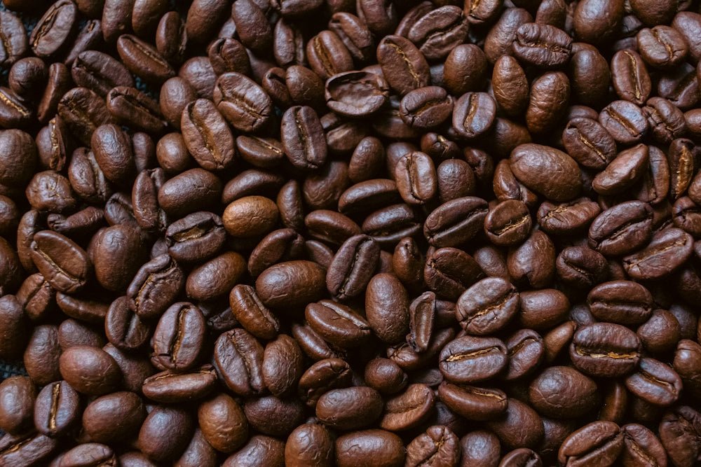 Roasted coffee beans are scattered closely together.