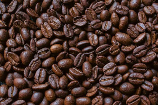 Roasted coffee beans are scattered closely together.