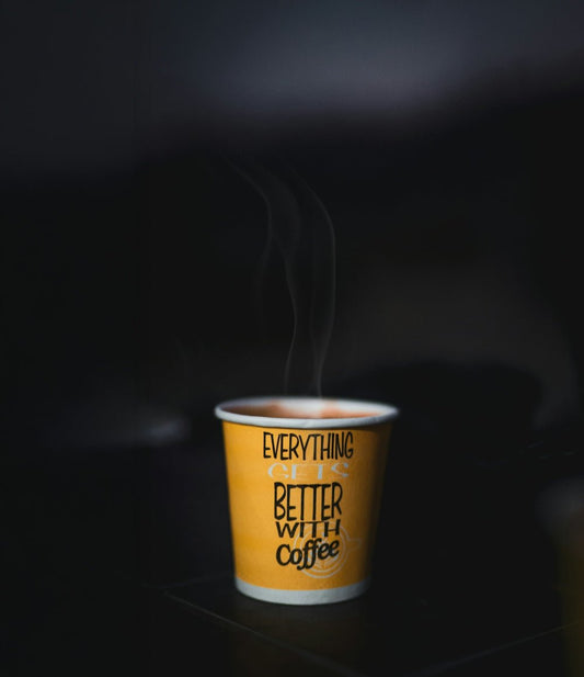 Steaming cup of coffee with text on yellow paper cup