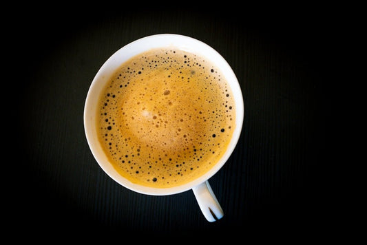 A cup of frothy coffee on a dark background