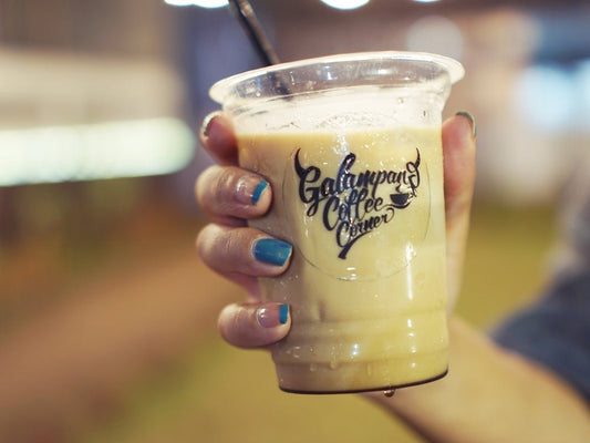 Hand holding a cold coffee drink with straw